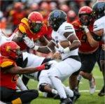 A Lakers football player tries to slip past Ferris State players.